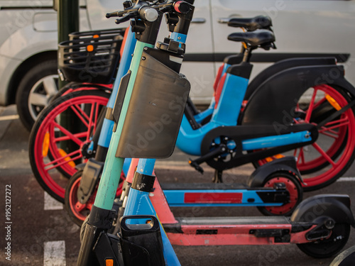 Close view of electric scooters and electric bicycles from share riding services in France, parked in an urban setting, reflecting micromobility, app based rental transport and low emission travel.