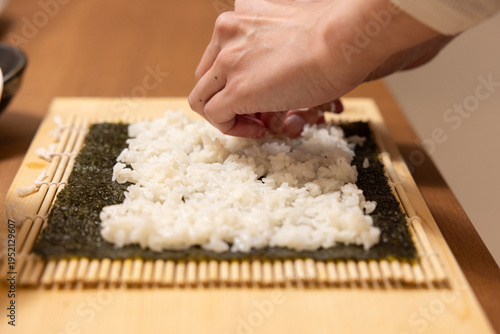 Close-up of a woman's hands making ehomaki sushi roll