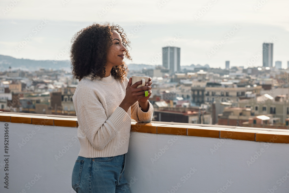Obraz premium Beautiful woman drinking a cup of tea while relaxing on her balcony at home