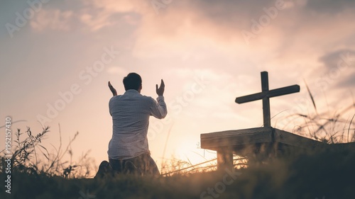 A man kneeling in prayer with raised hands before a cross.
