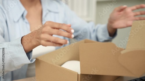 Ecommerce packing shipping fulfillment order small business owner smiling while sealing cardboard parcel box with tape preparing shipment delivery for online store customers from home workspace
