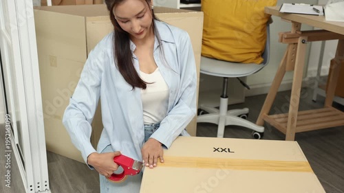 Small business warehouse scene of worker apply shipping label on parcel and taping cardboard box, organizing delivery tasks, order preparation and maintaining efficient packing workflow, multitasking