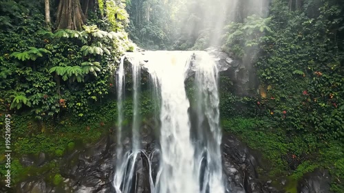 Stunning Waterfall in Lush Green Jungle with Sunlight Streaming Through Trees.