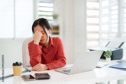Asian adult businesswoman feeling overwhelmed headache stress working long hours office desk with laptop burnout exhaustion pressure project deadline frustrating work environment