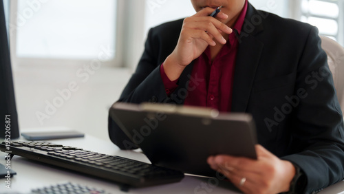 Adult Asian professional businessman thinking business strategy analyzing report documents holding pen in hand corporate office setting
