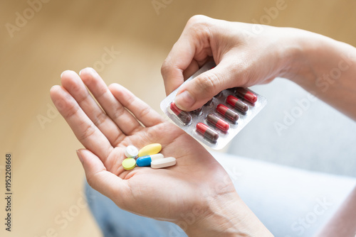 Sick ill asian young woman, girl hand taking tablet pill capsule out from blister pack, painkiller medicine from stomach pain, head ache, pain for treatment, take drug or vitamin at home, health care.