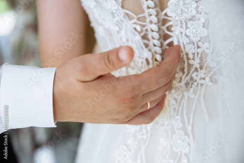 groom's hand on the bride's dress