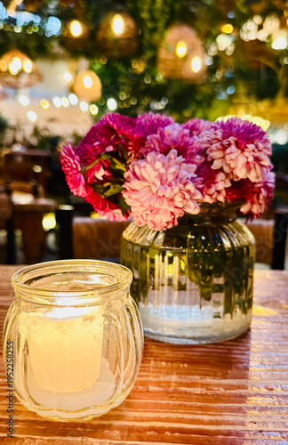 Warm candle light and flowers on wooden table, cozy and romantic atmosphere