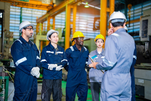 Cuadro en lienzo Industrial workers group standing with supervisor during briefing in manufacturing workshop with safety gear and helmets