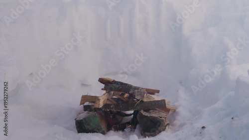 Wallpaper Mural Campfire smoldering in a snow pit surrounded by deep snow walls. Smoke rises from the stacked firewood while the fire slowly burns in winter conditions. High quality 4k footage Torontodigital.ca