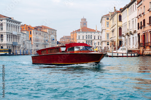 Schilderij op canvas Boat travels through the waterways of Venice with historic buildings in the back