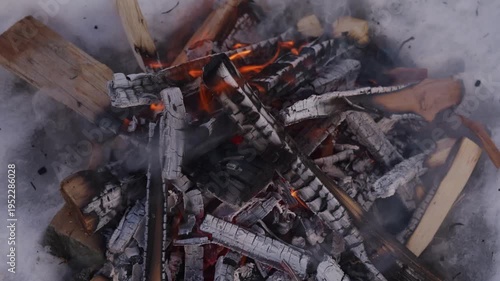Wallpaper Mural Closer overhead view of a winter campfire burning inside a snow pit. Bright flames appear between stacked firewood and dark charred logs while smoke rises into cold air. High quality 4k footage Torontodigital.ca