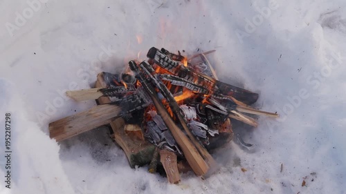 Wallpaper Mural Firewood stacked in a small campfire burns inside a snow pit during winter. Flames glow between wooden logs while the fire burns outdoors in cold conditions. High quality 4k footage Torontodigital.ca