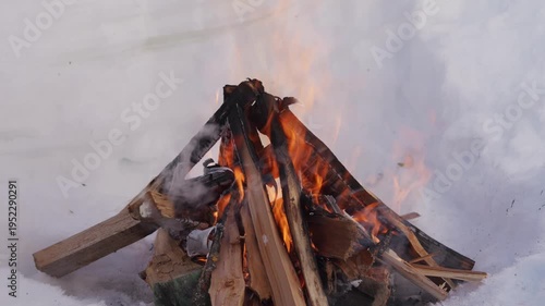 Wallpaper Mural Small winter campfire built from wooden logs burning inside a snow pit. Flames rise between the stacked firewood while the fire burns outdoors. High quality 4k footage Torontodigital.ca