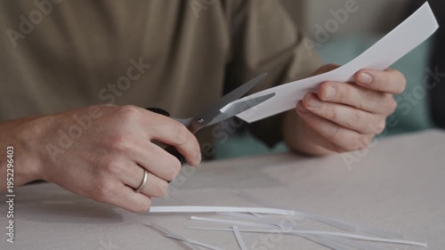Wallpaper Mural Close-up of scissors cutting a long thin strip from a sheet of white paper. Hands guide the blades carefully during a simple manual cutting process. High quality 4k footage Torontodigital.ca