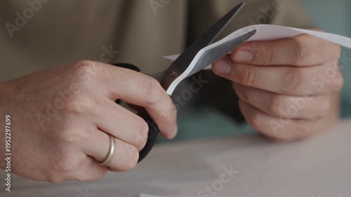 Wallpaper Mural Close-up of hands holding scissors after cutting a sheet of white paper. The blades open slightly while the paper piece is already separated on the table. High quality 4k footage Torontodigital.ca