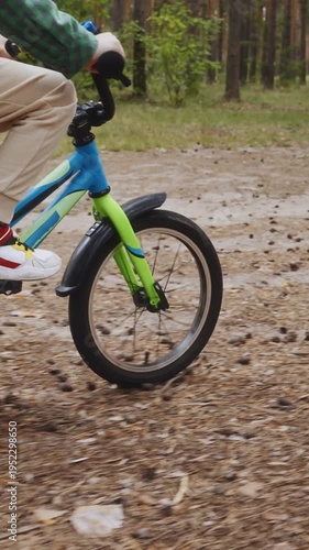 Wallpaper Mural Vertical side-tracking shot of a young boy cycling through a forest trail. The moving camera follows him parallel, highlighting dynamic motion, balance, and a joyful outdoor childhood moment. 4k Torontodigital.ca