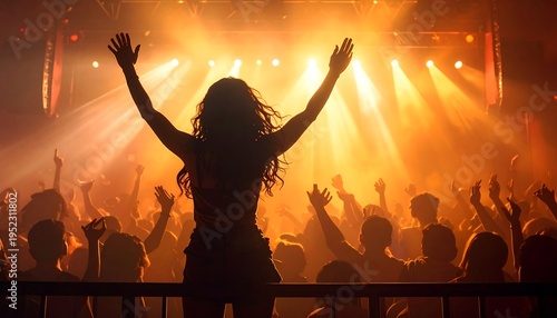 A woman stands on stage with arms raised before a crowd