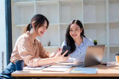 Group of happy Asian business people having a meeting at the office. Two women working together using modern laptops.