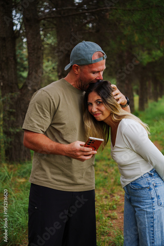 A couple of a white man and a Latino girl in casual clothes posing in a forest