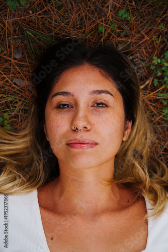 portrait of a young Latino brunette girl using Jeans and a blue shirt in a country setting with a lot of green and trees in the background