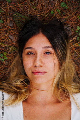 portrait of a young Latino brunette girl using Jeans and a blue shirt in a country setting with a lot of green and trees in the background