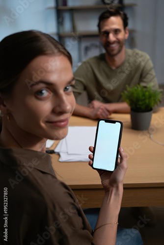 Homeowner couple reviewing solar savings app on smartphone at kitchen table