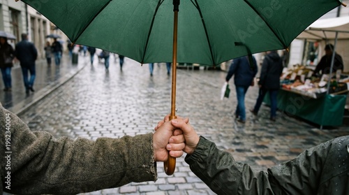 Couple Holding Hands Under a Green Umbrella Walking Together on a Rainy Cobblestone City Street