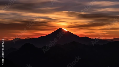 Majestic mountain silhouette against a vibrant sunset sky, showcasing the gradual transition of light and color over the peaks and valleys of the landscape