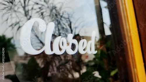 Closed sign on glass window with reflections of nature and blurred background