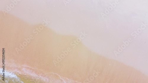 A serene view of an ocean wave reaching a sandy shore, creating a soft, warm atmosphere