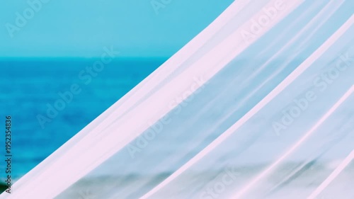Sheer fabric gently blowing in the wind against a backdrop of a clear blue sky and ocean. The fabric creates an ethereal, airy ambiance, and the scene evokes feelings of peace and serenity.