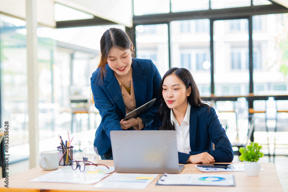 Obraz premium Group of happy Asian business people having a meeting at the office. Two women working together using modern laptops.