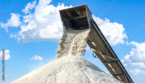 Conveyor belt dumping white material onto a large pile outdoors machine industrial