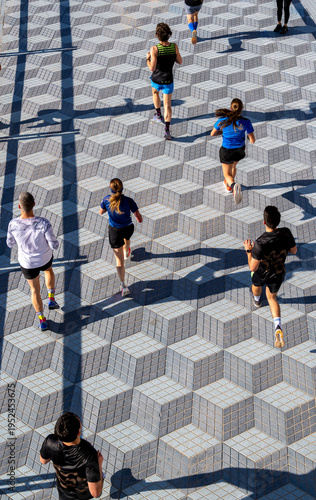 Group of marathon runners crossing geometric tiled plaza in organized road race event