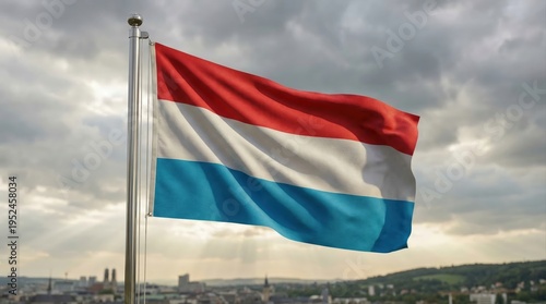 The national flag of Luxembourg waving majestically on a flagpole with a blurred cityscape and rolling hills in the background a vibrant symbol of the Grand Duchy