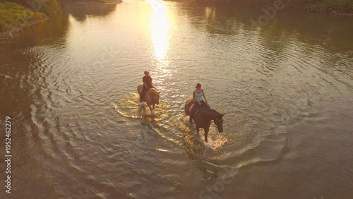 DRONE: Carefree girls leading their purebred horses down the refreshing stream.