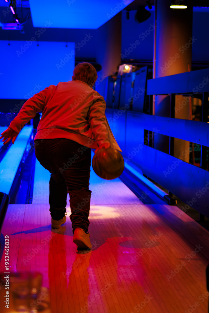 Obraz premium An older lady bowling in a lane with dark Blue Ambient Lighting