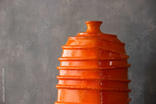 Close-up of an orange vase neck on a grey background