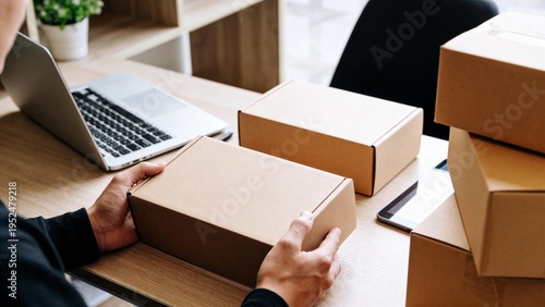 Close-up of a person handling a delivery box on a desk with a laptop. Ideal representation of small business logistics and packaging.