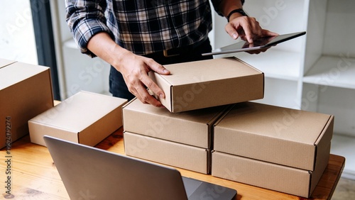 Business owner managing shipping and logistics with cardboard boxes and tablet. Ideal for small business and delivery services imagery.