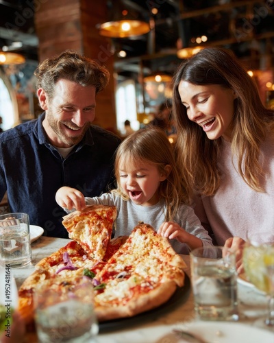 Happy family sharing a large pizza at a restaurant, laughing,