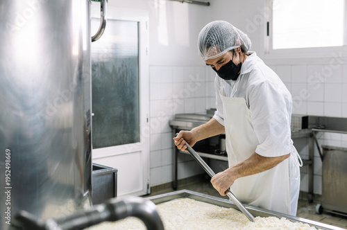 Billede på lærred Man working with cheese curds in creamery vat