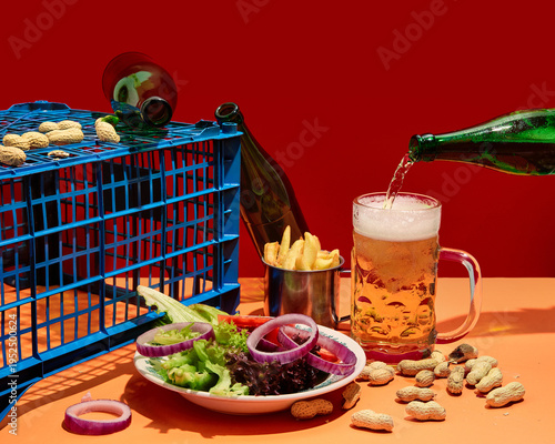 Φωτογραφία Beer pouring into glass with snacks and fresh salad on bright red background with copy space
