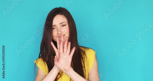Dissatisfied young woman showing stop gesture with hands and shaking head in denial isolated on blue background, unhappy female expressing refusal, disagreement, saying no with skeptical face