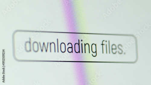 The process of downloading files on the monitor screen with text. Downloading files text displayed on a white screen background, indicating data transfer and online operations