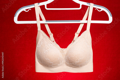 beige bra hanging on red background at horizontal composition