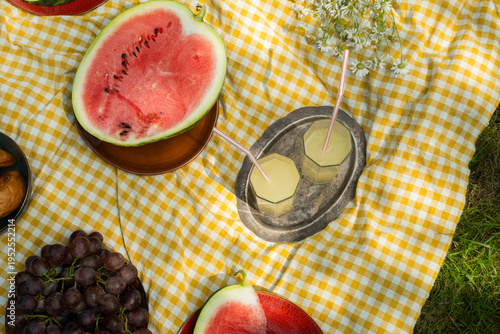 Summer picnic food. Two glasses of lemonade and fruits on yellow and white blanket. Summertime vibes. Top view.