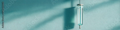 Intravenous drip bag hanging with clear liquid inside casting shadow on teal wall, medical equipment for fluid therapy in hospital or clinic setting