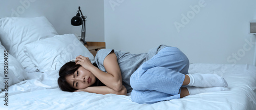 Foto Young Asian woman with suicidal thoughts and headphones lying in bedroom